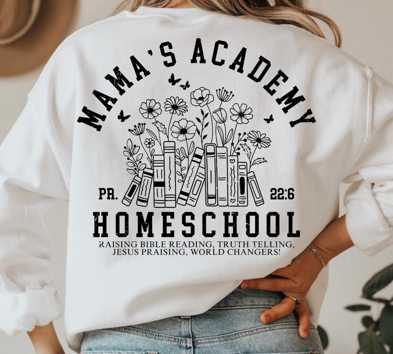 May include: White sweatshirt with black text that reads "Mama's Academy" in a circle with a floral design and books underneath. The text "PR. 22:6 HOMESCHOOL" is below the circle. The text "Raising Bible Reading, Truth Telling, Jesus Praising, World Changers!" is below the text "HOMESCHOOL".