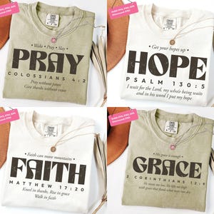 May include: Four t-shirts with inspirational messages. The shirts are in various colours, including off-white and olive green. Each shirt features a different word: PRAY, HOPE, FAITH, and GRACE, along with related Bible verses. Each shirt has a necklace.