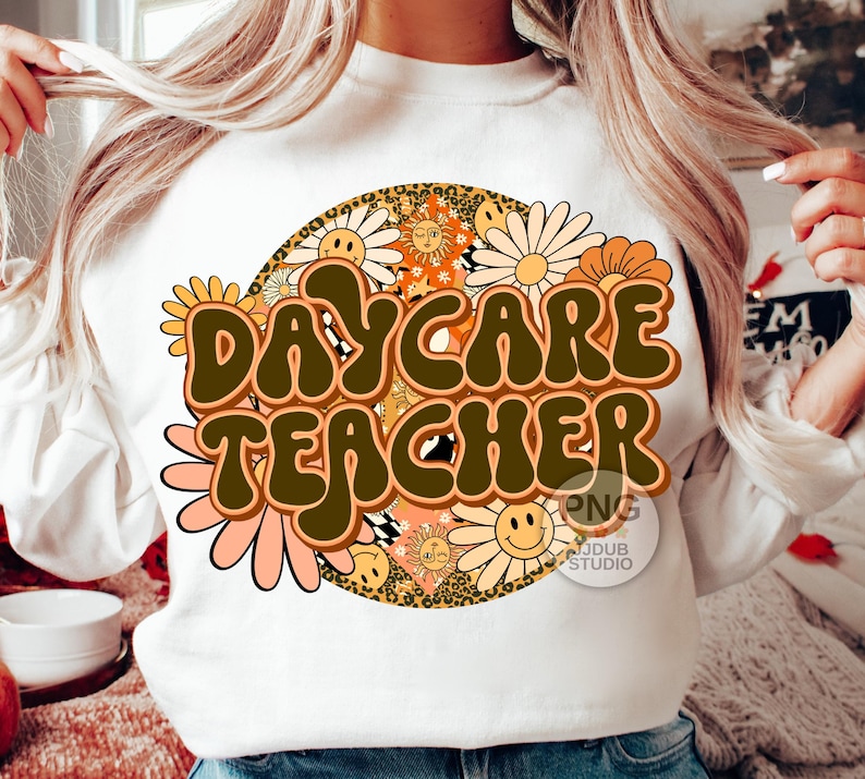 Peut inclure: Sweat-shirt blanc avec un motif r&eacute;tro repr&eacute;sentant un cercle de fleurs color&eacute;es et le texte "Daycare Teacher" en lettres brunes.