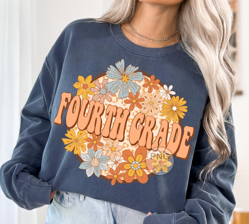May include: A navy blue sweatshirt with a graphic design of a circle of colorful flowers and the text "FOURTH GRADE" in a retro font.