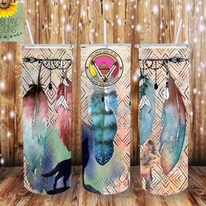 May include: A stainless steel tumbler with a design featuring watercolor feathers, geometric patterns, and the Great Seal of the Navajo Apache Nation. The tumbler is decorated with a dreamcatcher-like design with beads and feathers.