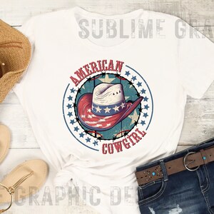 May include: White t-shirt with a red, white, and blue cowboy hat graphic. The graphic is surrounded by a circle of stars and the text "American Cowgirl".