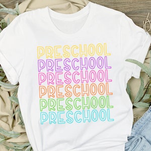 May include: White t-shirt with the word "PRESCHOOL" repeated six times in rainbow colors. Each word is outlined in a different color.