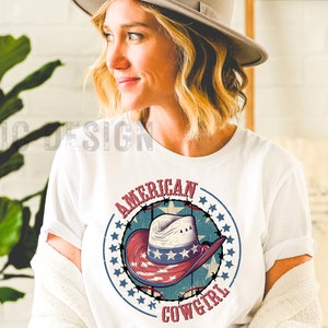 May include: White t-shirt with a red, white, and blue graphic of a cowboy hat with stars and the text "American Cowgirl".