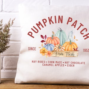 May include: A white pillow with a fall-themed design. The pillow features a watercolor illustration of pumpkins in various colors, with the text "PUMPKIN PATCH" and "Farm Fresh". Additional text includes "SINCE 1953" and fall activities.