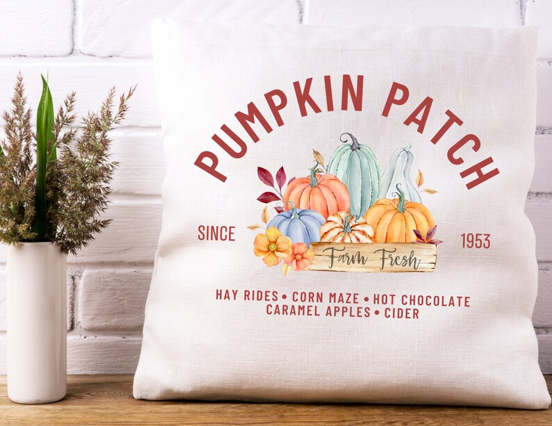 May include: A white pillow with a fall-themed design. The pillow features a watercolor illustration of pumpkins in various colors, with the text "PUMPKIN PATCH" and "Farm Fresh". Additional text includes "SINCE 1953" and fall activities.