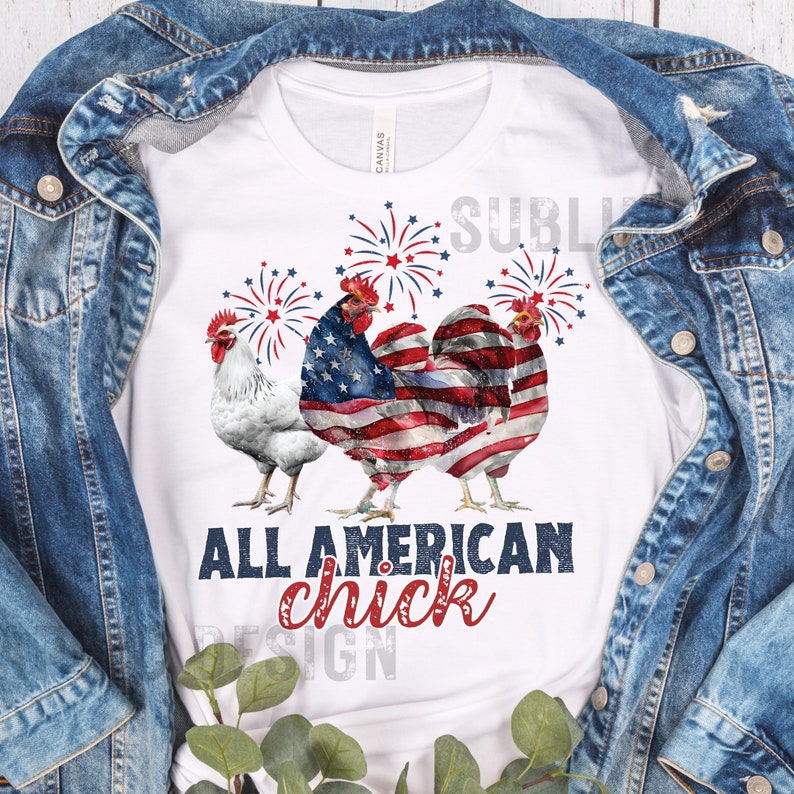 May include: White t-shirt featuring three rooster illustrations with patriotic American flag designs and fireworks. The text "ALL AMERICAN chick" is printed in red and blue. The shirt is displayed on a denim jacket.