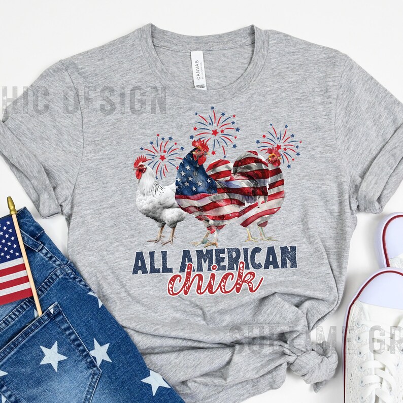 May include: A heather gray t-shirt featuring a graphic of three roosters with fireworks. The center rooster is designed with an American flag pattern. The text "ALL AMERICAN chick" is printed below the roosters in navy and red.