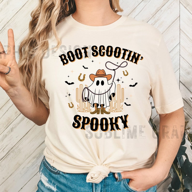 May include: A white t-shirt with a ghost wearing a cowboy hat and boots. The text "BOOT SCOOTIN' SPOOKY" is printed on the shirt.