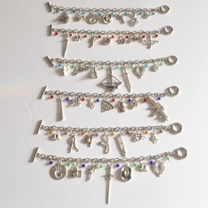 May include: Seven silver charm bracelets featuring a variety of charms, including a handprint, a camera, a sword, a compass, a book, a heart, a ship, a gun, a baseball bat, a pizza slice, a crown, a bell, a knife, a pair of wings, a boot, a syringe, a musical note, a key, a flower, a horseshoe, a star, and some colourful beads.