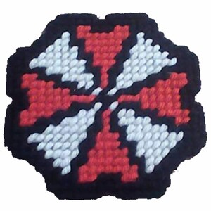 May include: A handmade, decorative coaster with a black border. The coaster features a central design of red and white geometric shapes, creating a symmetrical pattern. The coaster is likely made from yarn or a similar material.