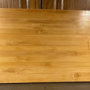 May include: A rectangular bamboo cutting board with rounded corners. The board has a natural wood grain pattern and the word "goodcook" is printed on the right side. This kitchen item is ideal for food preparation.