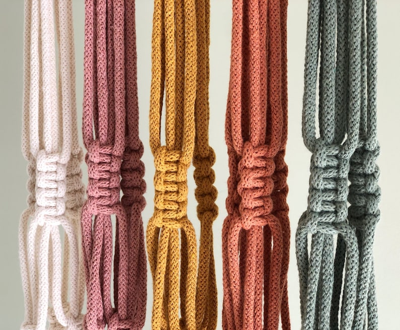 Pu&ograve; includere: Cinque portavasi in macram&egrave; di diversi colori: bianco, rosa, giallo, arancione e grigio. Ogni portavasi &egrave; realizzato con un cordino spesso annodato e presenta un design unico.