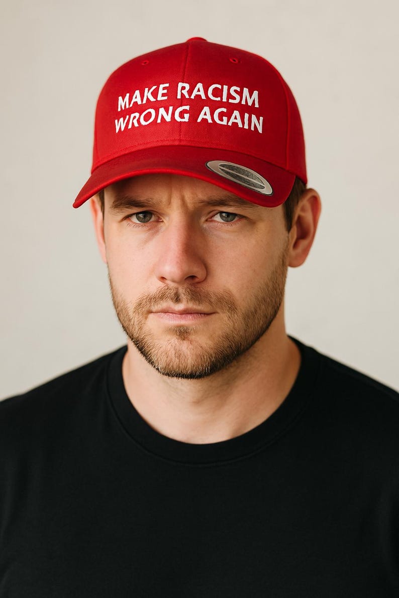 May include: A red baseball cap with the text "MAKE RACISM WRONG AGAIN" in white lettering.