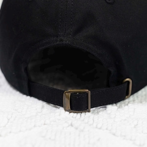 May include: Black baseball cap with an adjustable strap and a brass buckle.