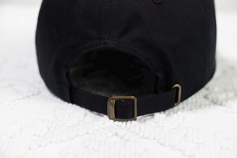 May include: Black baseball cap with an adjustable strap and a brass buckle.