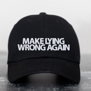 Może przedstawiać: Czarna czapka bejsbolówka z białym haftem z napisem "Make Lying Wrong Again".