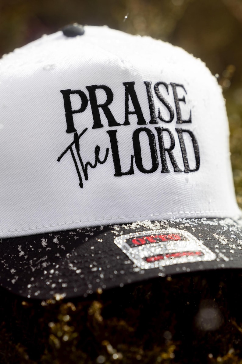 May include: White trucker hat with a black brim and black embroidered text that reads "PRAISE the LORD".