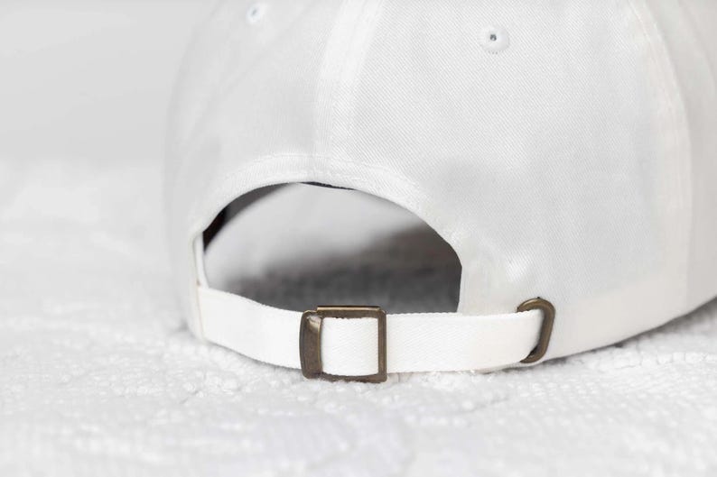 May include: White baseball cap with an adjustable strap and a brass buckle.