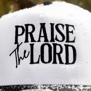 May include: White baseball cap with black embroidery that reads "Praise the Lord".