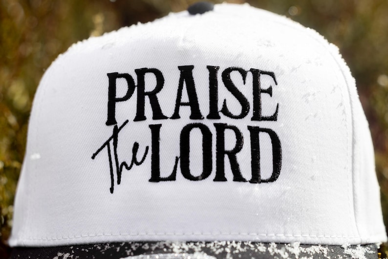 May include: White baseball cap with black embroidery that reads "Praise the Lord".
