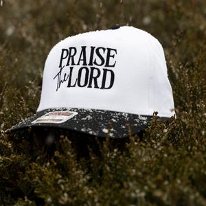 May include: A white and black baseball cap with the text "Praise the Lord" embroidered in black on the front.