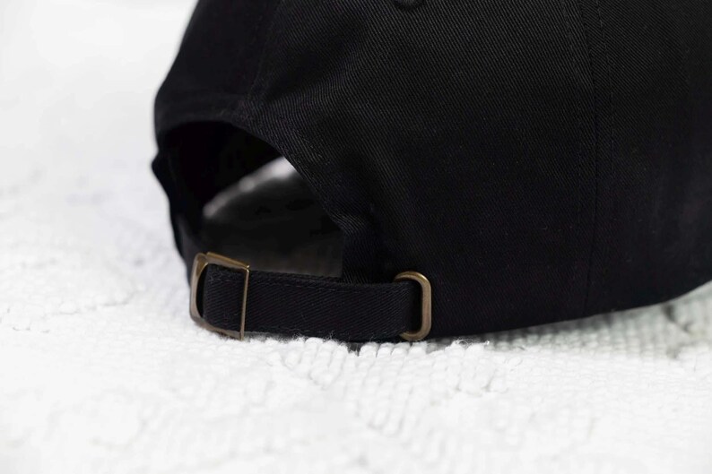 May include: Black baseball cap with a brown adjustable strap and buckle closure.