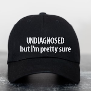 May include: Black baseball cap with white embroidered text that reads "UNDIAGNOSED but I'm pretty sure".