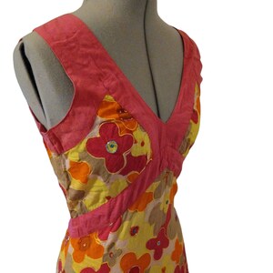 Puede incluir: Vestido sin mangas con escote en V, exhibido en un maniqu&iacute;. El vestido presenta un estampado floral en tonos rojos, naranjas, amarillos y marrones, con detalles en rosa. El vestido est&aacute; adornado con lentejuelas.