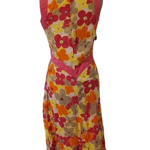 Puede incluir: Vestido sin mangas con estampado floral en tonos amarillos, naranjas y rosas. El vestido presenta un acento rosa en forma de V en la cintura y un panel rosa liso en los hombros. El vestido se exhibe en un maniqu&iacute;.