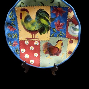 May include: A blue and white ceramic plate with a patchwork design featuring roosters, flowers, and polka dots.
