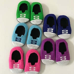 May include: Set of eight felt baby shoes in various colours, including green, blue, pink, and purple. Each shoe has a white embroidered design on the toe.
