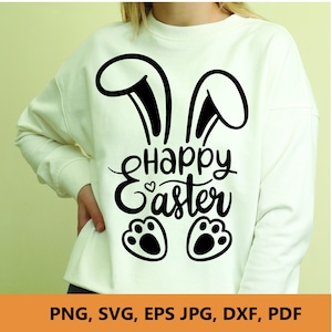 以下が含まれることがあります： ウサギの耳、"Happy Easter"の文字、ウサギの足跡が描かれた黒いグラフィックデザインのクリーム色のスウェットシャツ。画像の下部には、ファイル形式のオプションが表示されています：PNG、SVG、EPS、JPG、DXF、PDF。