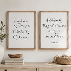 May include: Two rectangular wall art prints in light wood frames featuring black cursive text on a white background. The left print reads, "Here I raise my Ebenezer, hither by Thy help I've come;" and the right print reads, "And I hope by thy good pleasure safely to arrive at home 1 SAMUEL 7:12."