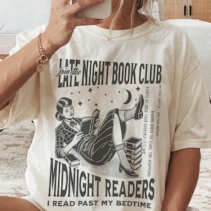 May include: A white t-shirt with a black and white illustration of a woman reading a book. The text on the shirt reads "Join the Late Night Book Club Midnight Readers I Read Past My Bedtime".