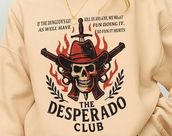 May include: Beige sweatshirt featuring a skull wearing a cowboy hat, crossed pistols, and flames. Text reads "The Desperado Club" and phrases like "Kill us anyway, we might fun doing it." and "If the dungeon's go as well have."