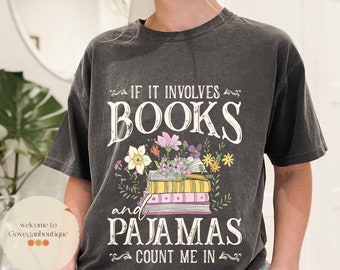 May include: A dark gray t-shirt with a white graphic that says "If it involves books and pajamas count me in". The graphic also features a stack of books with flowers around them.