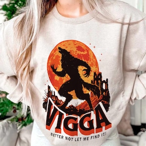 May include: Beige sweatshirt featuring a black werewolf silhouette howling at a large orange moon. The graphic includes the text "VIGGA" in red and black, with the phrase "BETTER NOT LET ME FIND IT!" below.