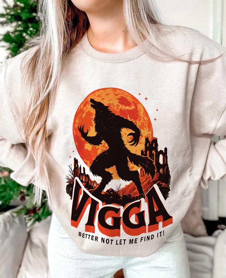 May include: Beige sweatshirt featuring a black werewolf silhouette howling at a large orange moon. The graphic includes the text "VIGGA" in red and black, with the phrase "BETTER NOT LET ME FIND IT!" below.