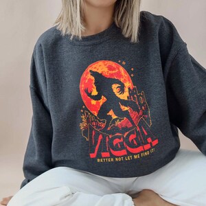 May include: Dark gray sweatshirt featuring a werewolf silhouette against a red moon. The design includes a castle and the text "VIGGA! BETTER NOT LET ME FIND IT!" in red and orange. A casual, spooky themed garment.