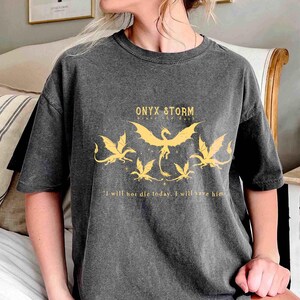 May include: A dark gray t-shirt with a graphic print of five dragons and the text "ONYX & STORM" and "I will not die today. I will save him."