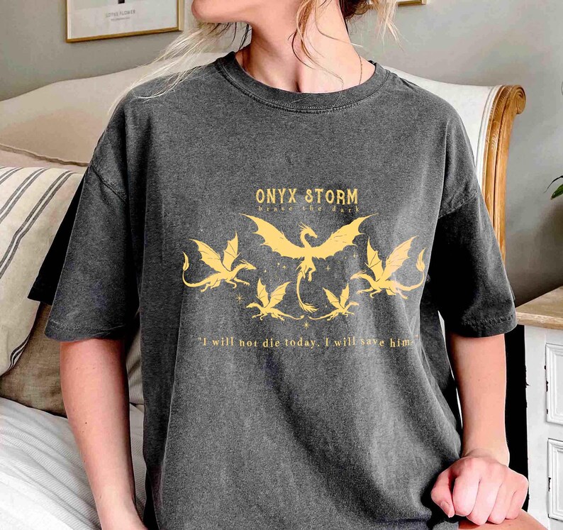 May include: A dark gray t-shirt with a graphic print of five dragons and the text "ONYX & STORM" and "I will not die today. I will save him."