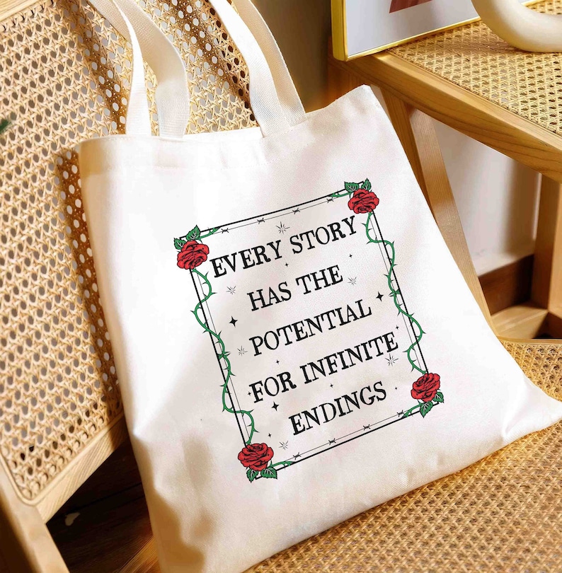 May include: White canvas tote bag with black handles and a black framed quote that reads "Every story has the potential for infinite endings." The quote is surrounded by a black vine with red roses.