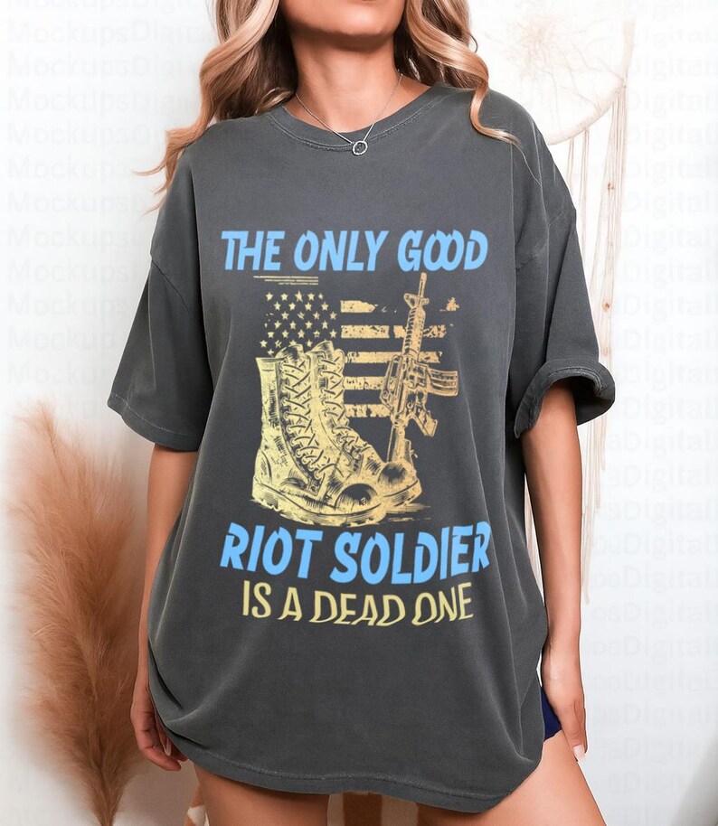 May include: Dark gray t-shirt with a graphic design. The design features a combat boot, a rifle, and an American flag, with the text "THE ONLY GOOD RIOT SOLDIER IS A DEAD ONE" in blue and yellow.