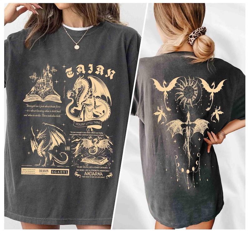 May include: A black t-shirt with a graphic print of a dragon and a castle. The text "TAJAN" is printed on the shirt. The back of the shirt has a graphic print of a dragon with a sun and moon.
