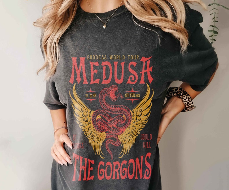 K&ouml;nnte beinhalten: Schwarzes T-Shirt mit einem grafischen Druck einer roten Schlange mit Fl&uuml;geln und dem Text "Goddess World Tour Medusa 22.00 HR 9TH FEB. 1982 The Gorgons Could Kill"
