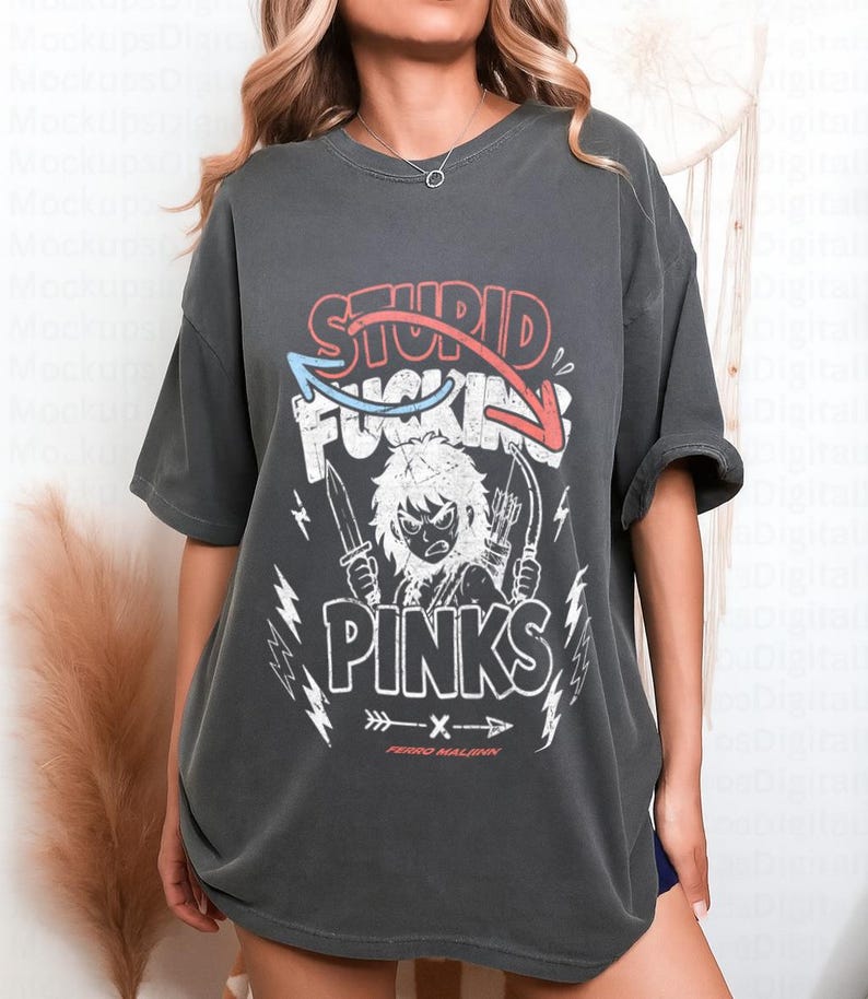 May include: Dark grey t-shirt with a graphic design. The design features the words "STUPID FUCKING PINKS" in red and white, with an illustration of a character holding a knife and bow and arrow. The text "FERRO MALIGN" is below the graphic.