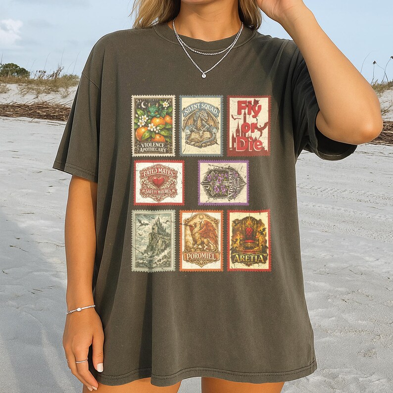 May include: Dark olive green t-shirt featuring a collection of vintage-style postage stamp designs. The stamps showcase various illustrations, including botanical elements, dragons, and text such as "Fly or Die" and "Violence Apothecary".