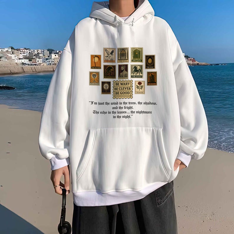 May include: White hoodie with a front pocket and a drawstring hood. The front features a collection of vintage-style postage stamp illustrations and the text "BE WARY BE CLEVER BE GOOD" and a quote.