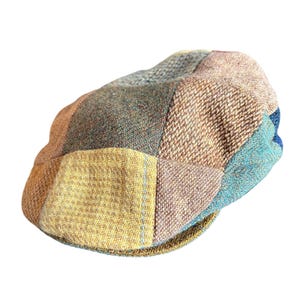May include: A patchwork newsboy cap in a variety of colors including tan, blue, green, and yellow. The cap is made of a textured fabric and has a classic, rounded shape. The cap is a stylish accessory.